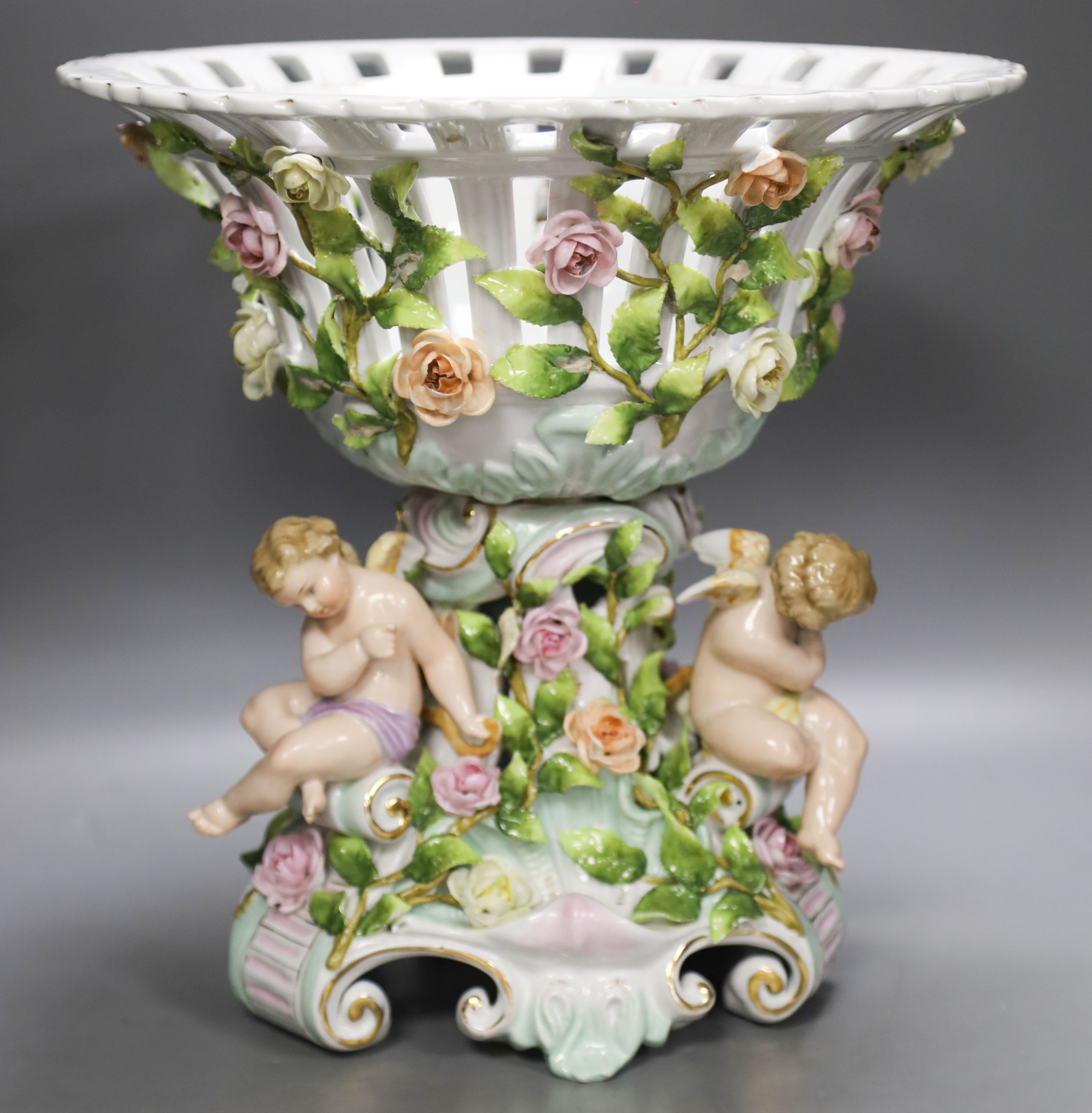 A Plaue porcelain Meissen style fruit stand, encrusted with flowers and winged amorini 30.5cm